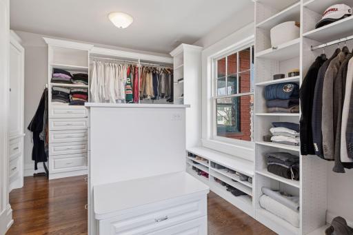 Generous primary walk-in closet with center island storage and custom cabinetry.