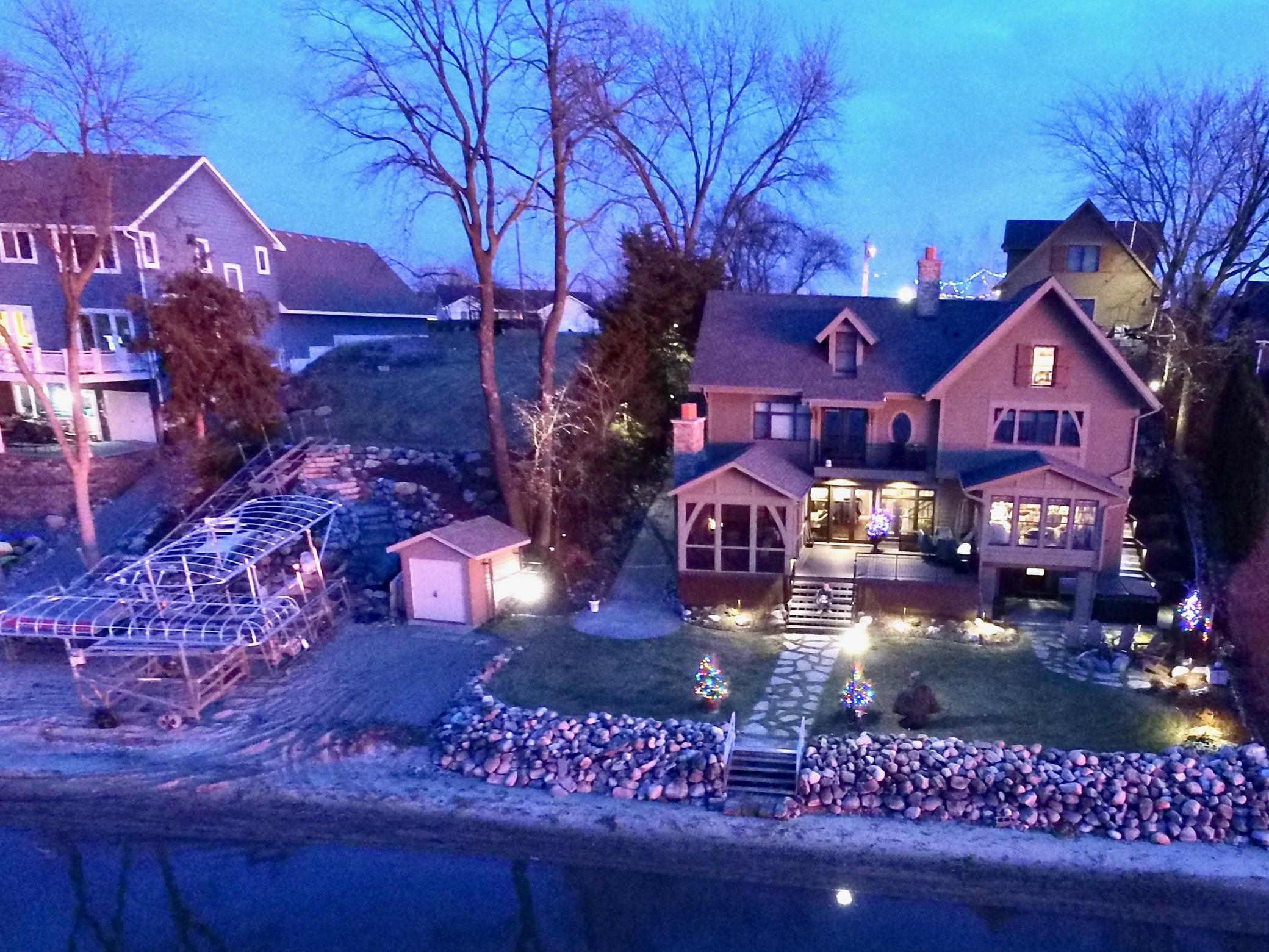 Evening view of the property after the dock came in for the year. Note the extensive landscaping completed on the vacant lot. Note, you can see on the left side of the house the paver ramp to get up and down. Same can be found on the vacant lot