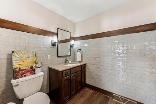 Here is a view of the recently added half bath off the garage featuring LVP flooring, custom vanit, and subway tile.