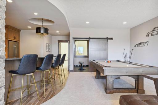 The lower level family room is airy and warm. Plenty of room to watch a game, play a game, or relax at the bar.