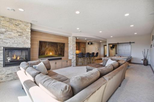 The lower level family room is airy and warm. Plenty of room to watch a game, play a game, or relax at the bar.