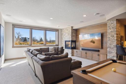 The lower level family room is airy and warm. Plenty of room to watch a game, play a game, or relax at the bar.