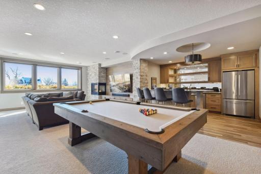 The lower level family room is airy and warm. Plenty of room to watch a game, play a game, or relax at the bar.
