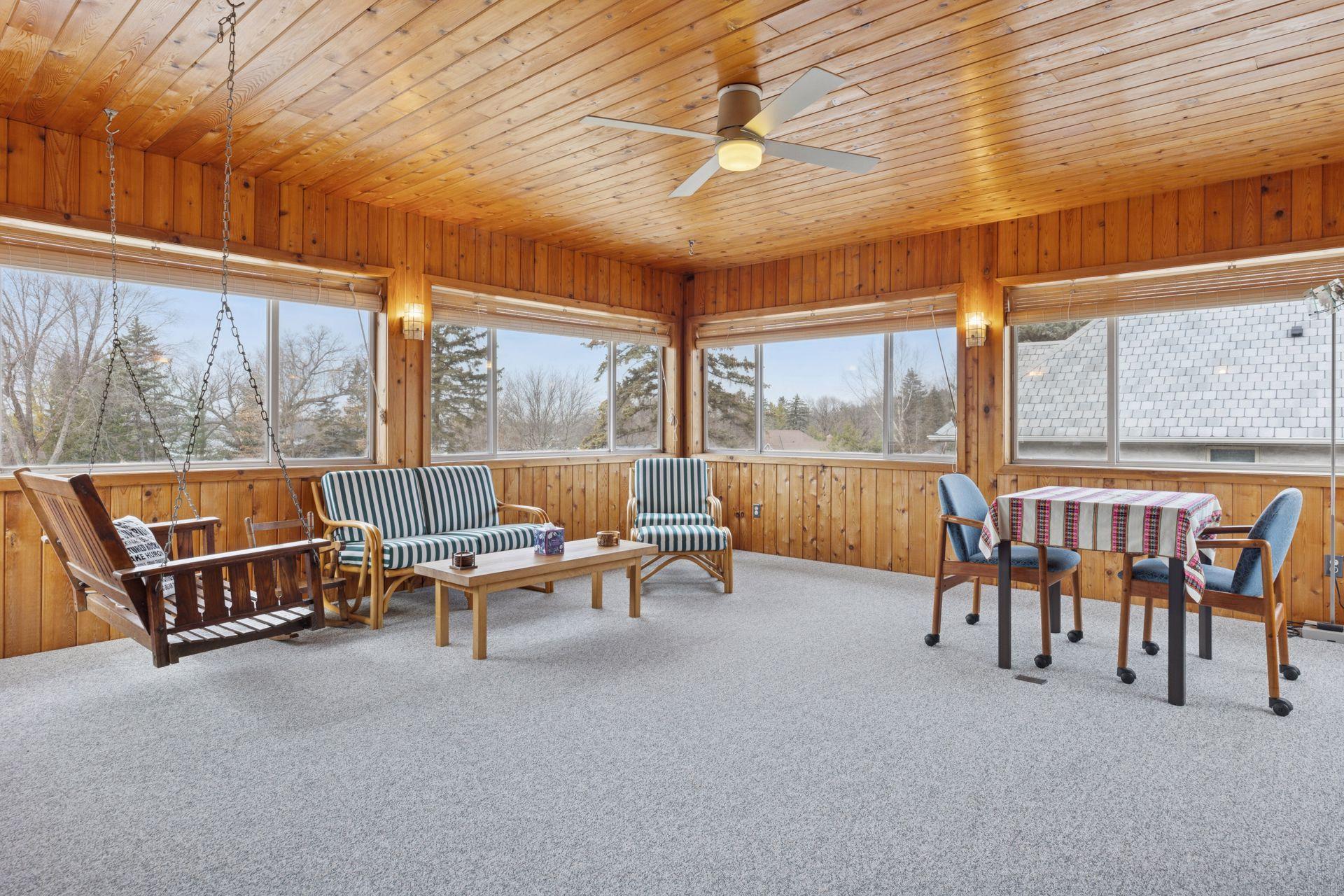 The three-season porch, featuring wood-paneled walls and a freestanding gas fireplace, offers a perfect retreat year-round.