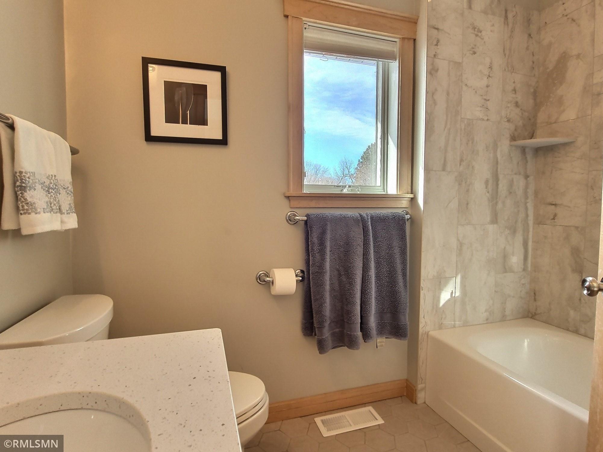 The primary full bath that just received a facelift with new tile floor and tile surround giving it todays modern flair.