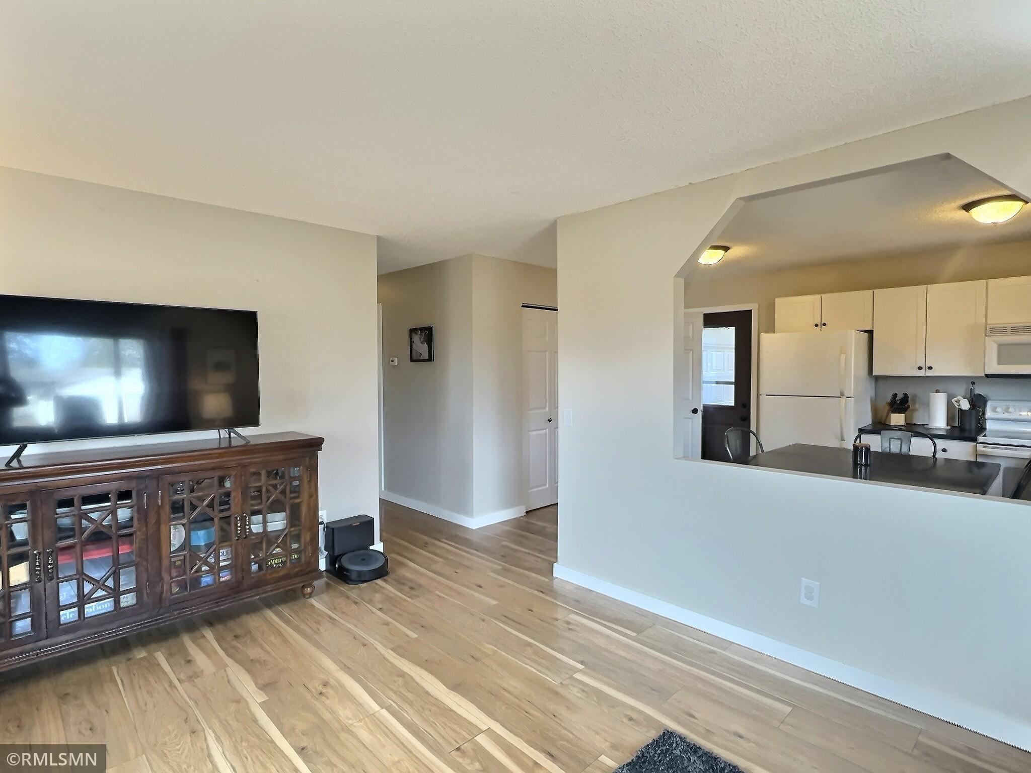 Another view of the living room with updated flooring, hallway leads to three bedrooms and a full bathroom.