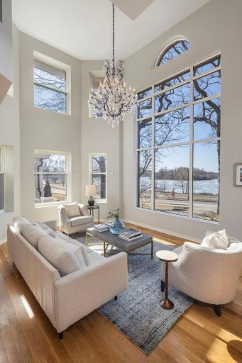 Dramatic two-story living room with a wall of windows captures westerly views of the lake while allowing natural light to flow throughout the space.