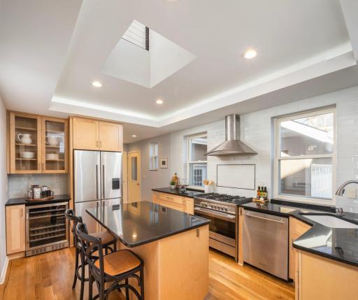 Thoughtfully kitchen updates include center island with seating, beverage refrigerator, ample storage, butler's pantry, and open ceiling to second level.