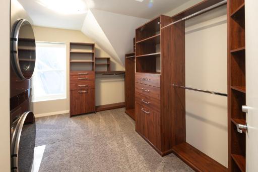 Primary owners walk in closet with washer and dryer. Custom built in closet system.
