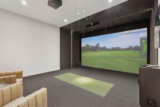 Lower level multipurpose room with a golf simulator
