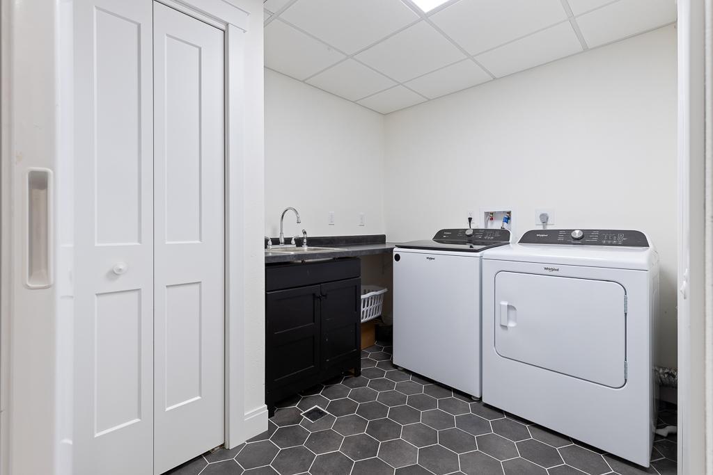 The laundry room boasts the stylish hexagon tiles, a bonus sink, and storage space