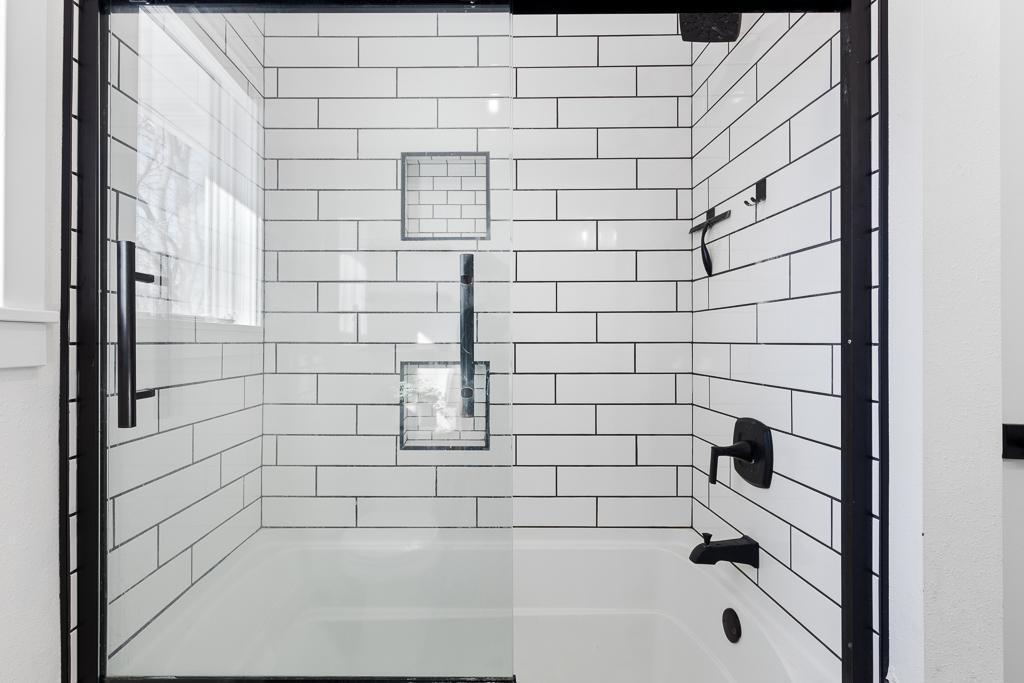 Stunning bathtub and shower surrounded white subway tiles