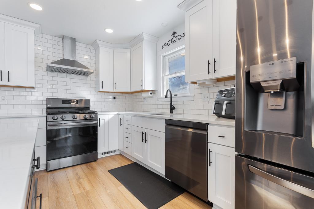 Beautiful updated appliances feature a gas stove and hood, dishwasher, fridge, and microwave