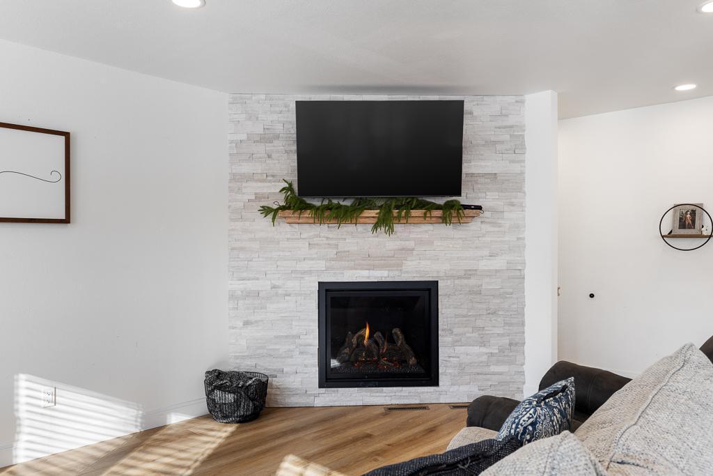 A gorgeous centerpiece for the living room - a stone wall with gas fireplace and wood mantle