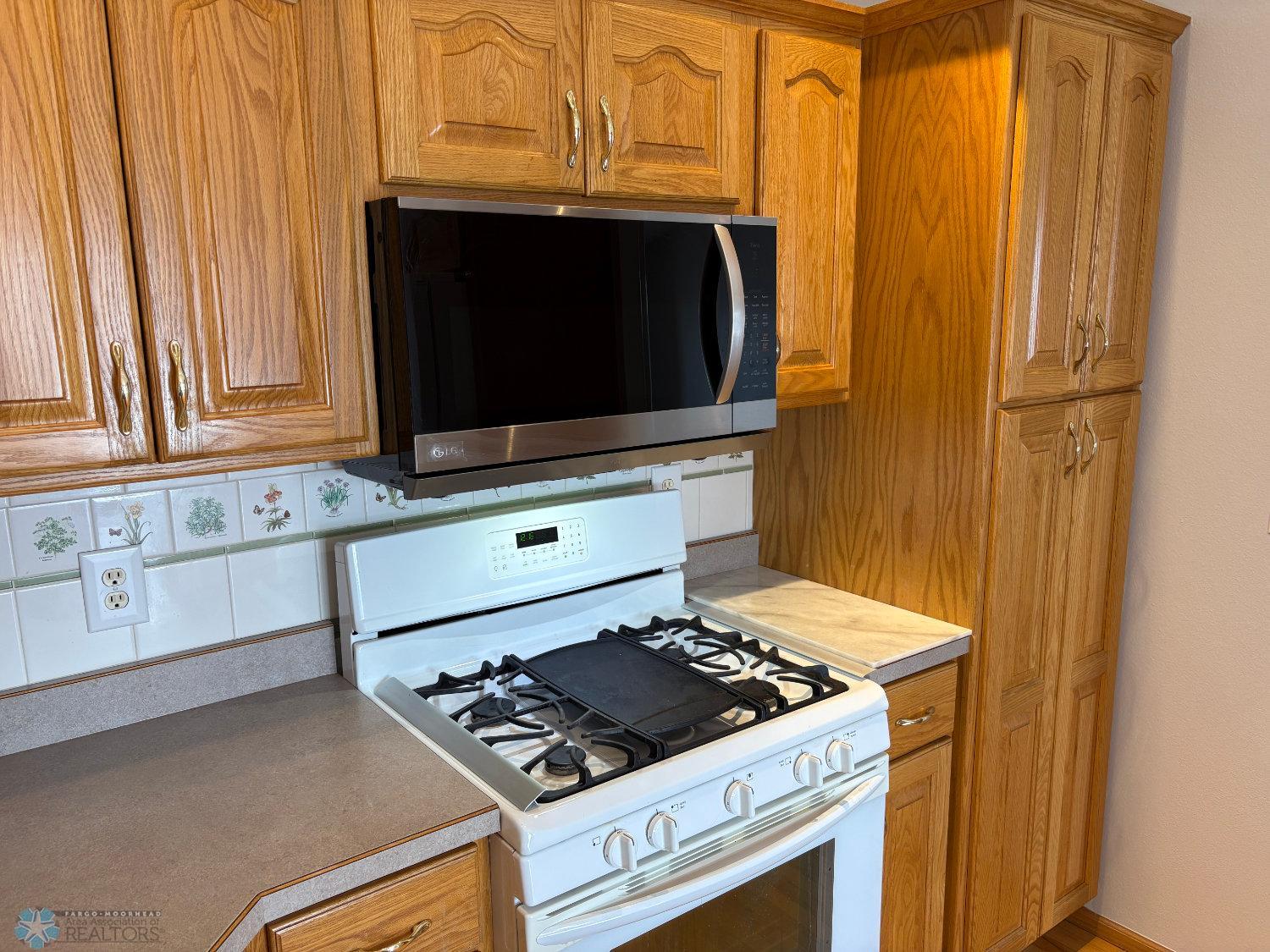 Kitchen has a tall pantry cabinet and natural gas range and oven.jpg