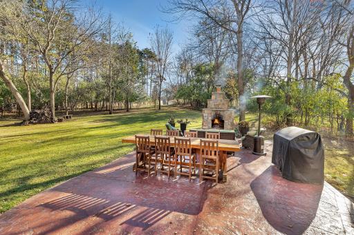 The outdoor living space features custom stamped & stained concrete patio with handsome stone fireplace!