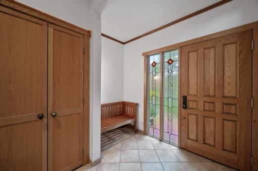 The tiled entry was expanded to create more landing space. Note the oversized door and the beautiful stained glass sidelight windows.