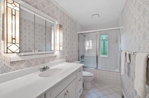 The en suite bathroom with its timeless white tile and beautiful stained glass window.