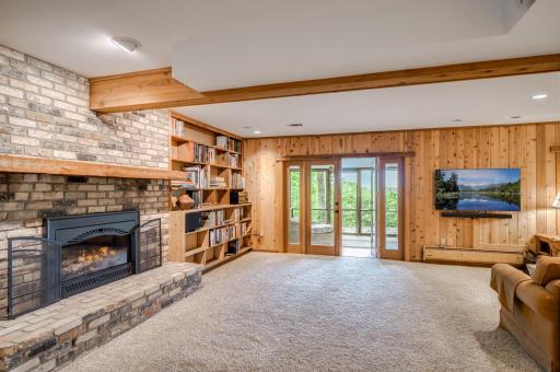 The spacious lower level family room has a gas fireplace flanked by built-in shelving.