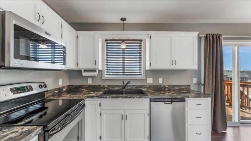 Kitchen features white painted cabinetry and window overlooking backyard.