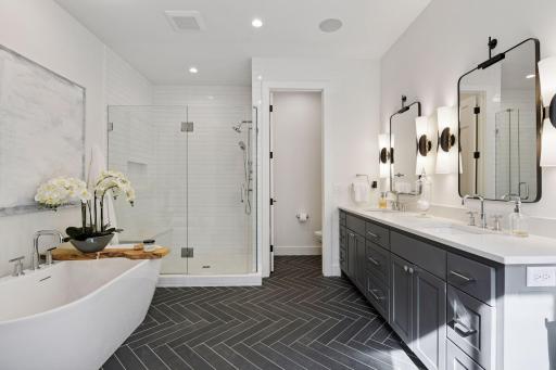 Gorgeous primary bath with Herringbone tile, White Quartz countertops, freestanding tub and shower featuring subway tile walls and herringbone tile floor.