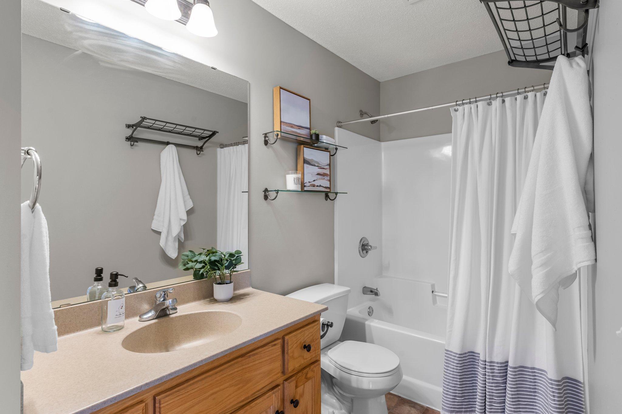 The upper level shared bathroom features a tub/shower combo and a single vanity with ample storage and tile floors.