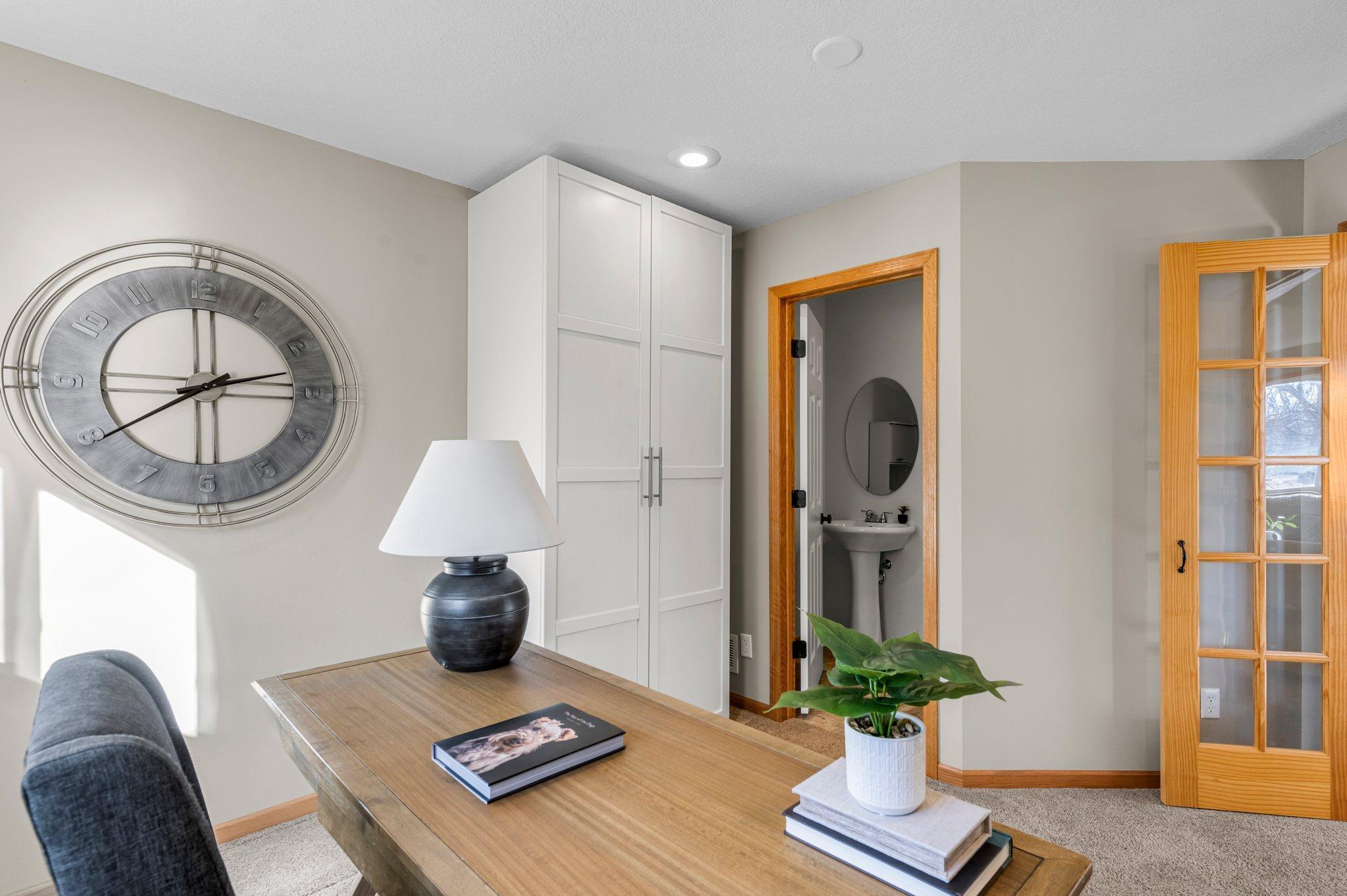 A different perspective of the lower-level bedroom or office space, featuring a private half bathroom.