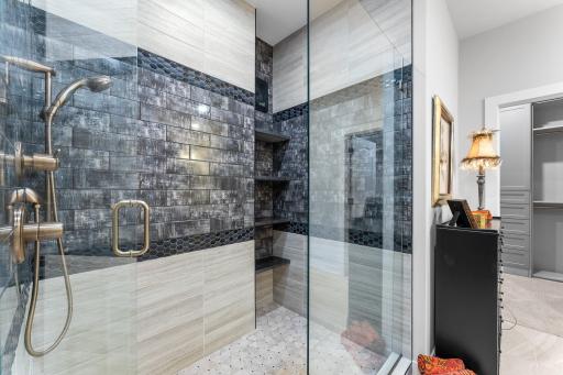 The primary bedroom bathroom has a classy walk-in shower with floor to ceiling tile.