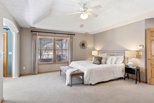 Primary bedroom with trayed ceiling & balcony overlooking the lake.