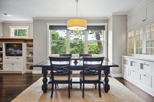 Informal dining are features a wall of windows and built-in buffet with glass-front uppers with accent lighting