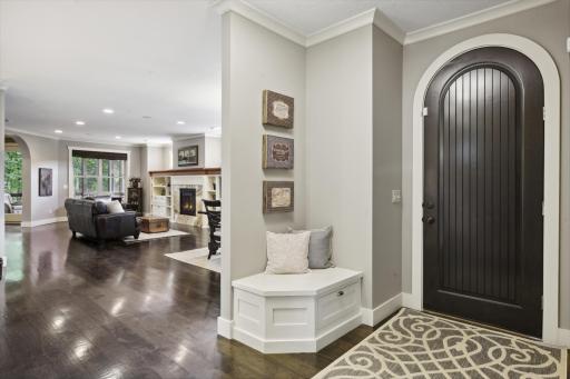Beautiful arched wood front door enters to a spacious foyer with bench seat