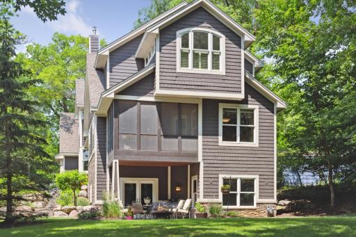 Expanded paver patio with covered and open seating areas extends from the walkout lower level and past to the level backyard.