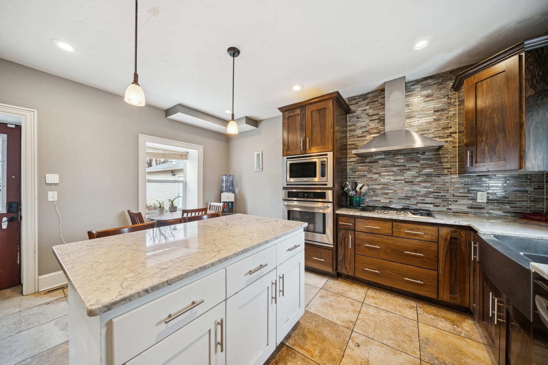 The gas stove top and SS hood, along with the gorgeous backsplash, finish off this Chef's dream kitchen!