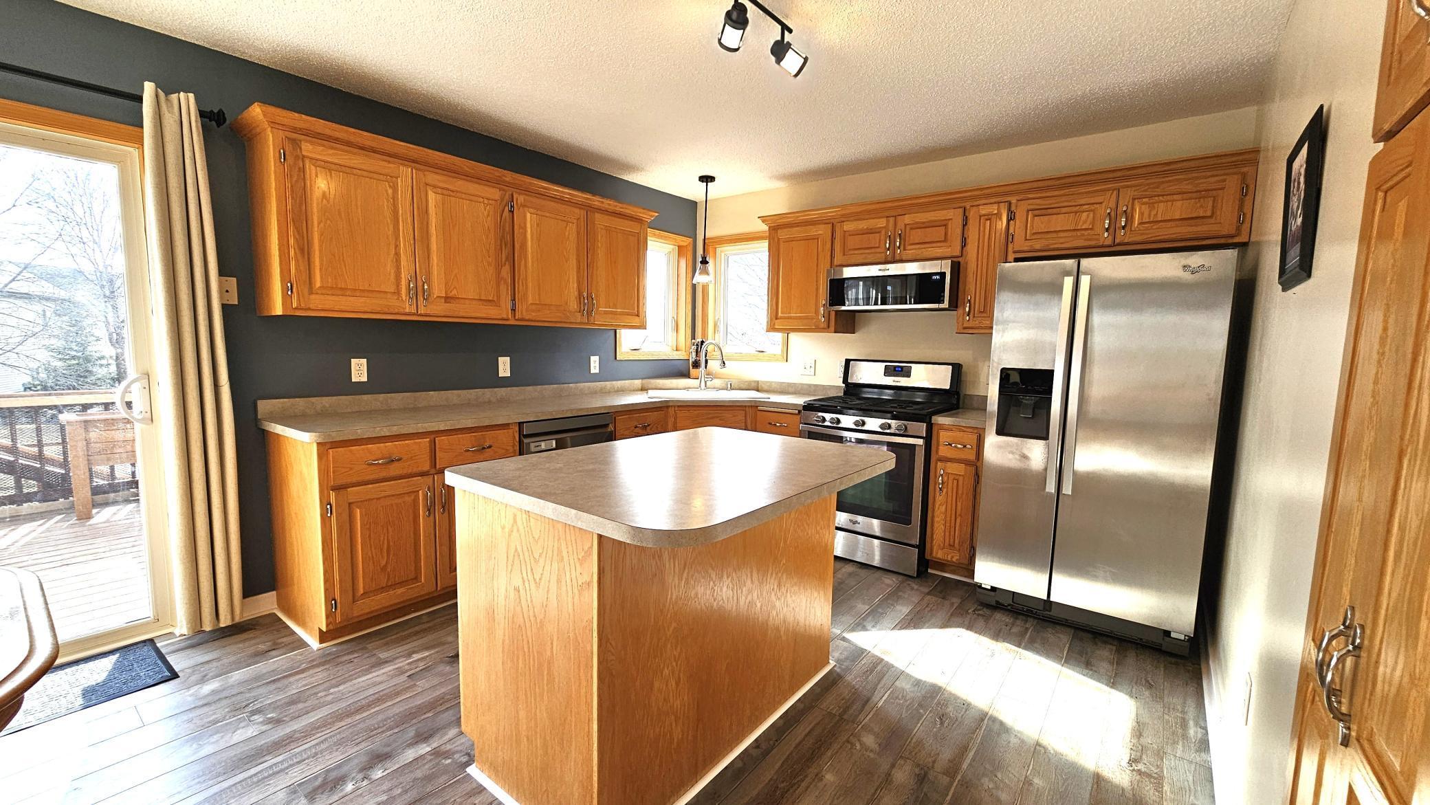 Brightly lit kitchen w/stainless appliances.