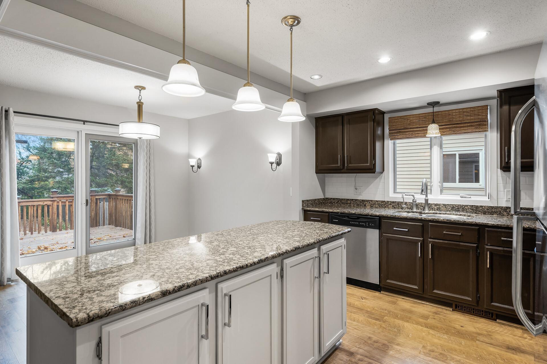 Kitchen and informal dining area have loads of lighting with recessed lights, wall sconces, pendants over the island and dining ceiling fixture.