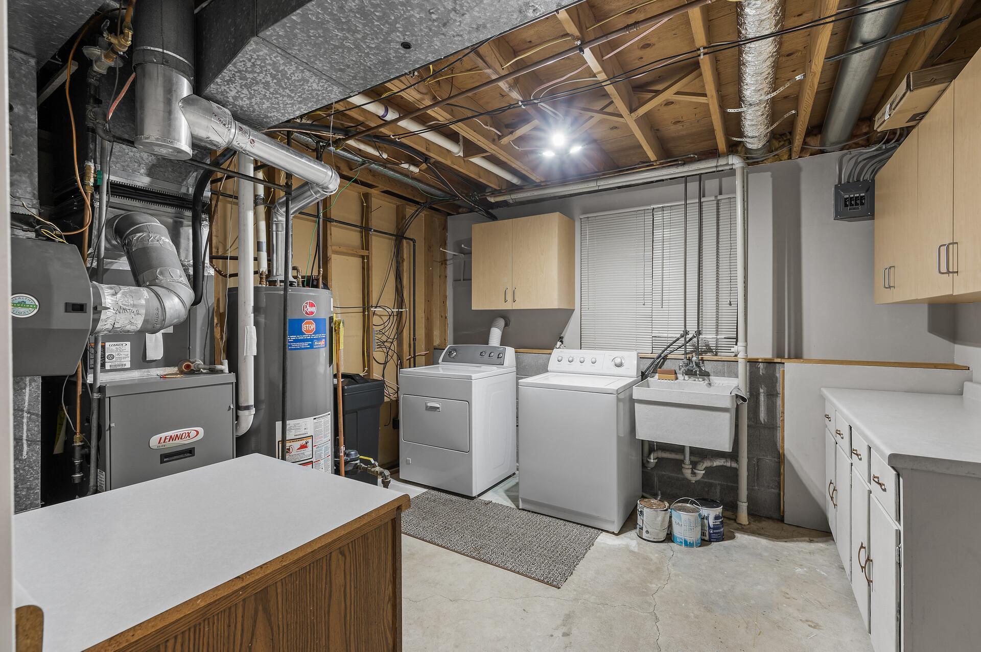Laundry and mechanical room with extra cabinets for storage and folding.