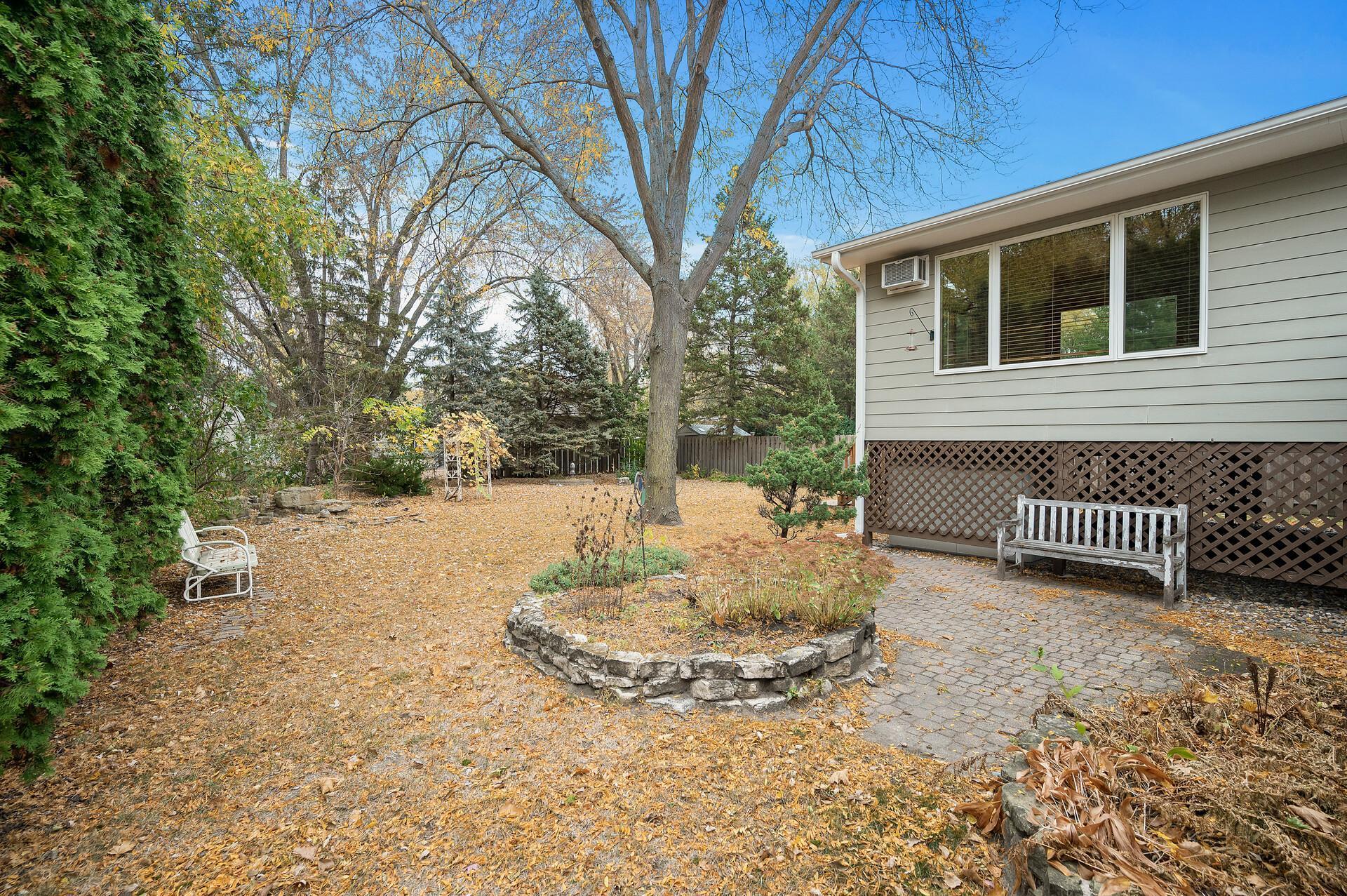 Paver patio just behind the garage with perennials boarding it.
