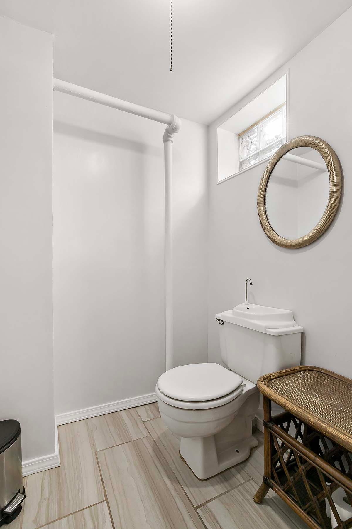 The second bath is located in the basement and features glass block windows and this creative space-saving tank/sink combo.