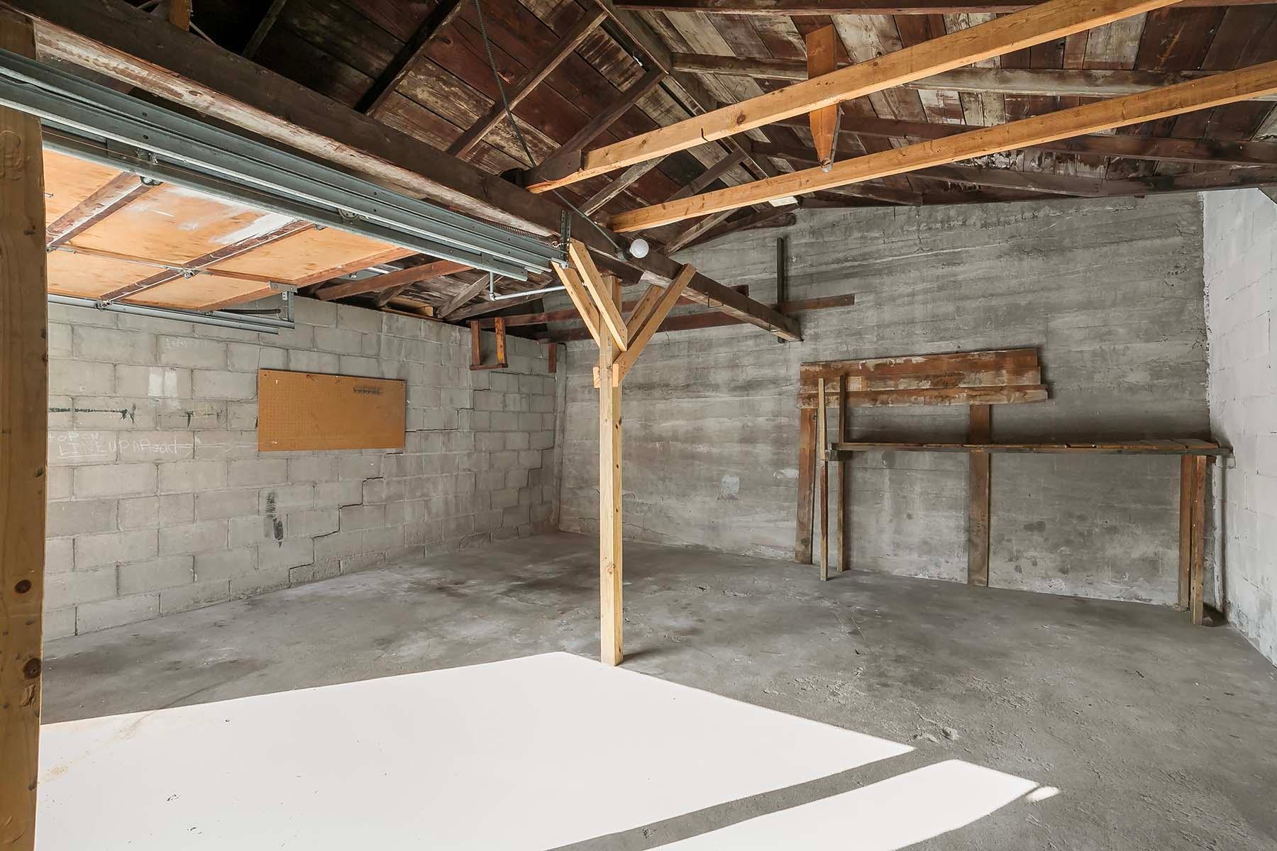 The garage interior is large with exceptionally high ceilings and plenty of space for vehicles and storage plus a workspace.