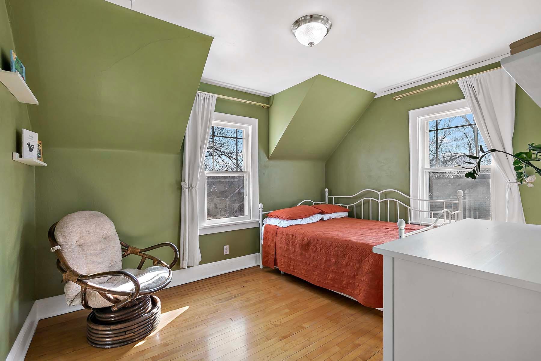 Bedroom number two in serene sage green, also featuring windows on two sides.