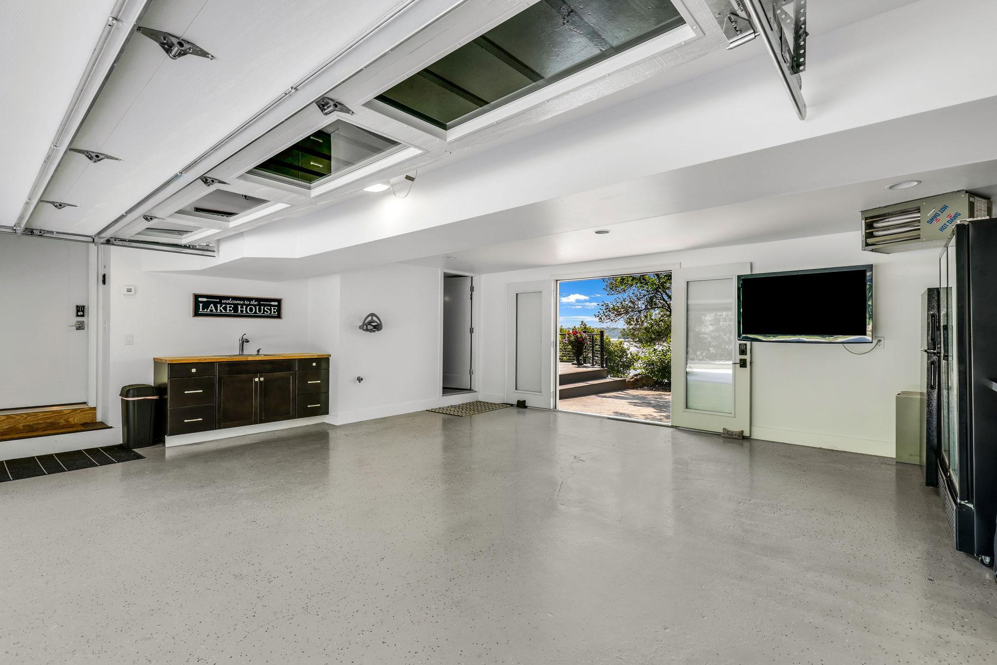 The garage is fully finished, heated and features an epoxy floor. It offers a sink and storage plus the 6th bathroom (door to the left in back). Double doors lead to the patio and lake. Another great space to host family and friends!