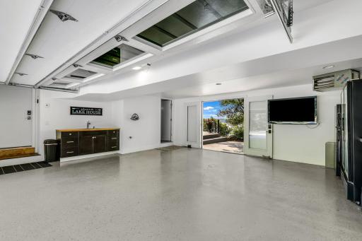 The garage is fully finished, heated and features an epoxy floor. It offers a sink and storage plus the 6th bathroom (door to the left in back). Double doors lead to the patio and lake. Another great space to host family and friends!