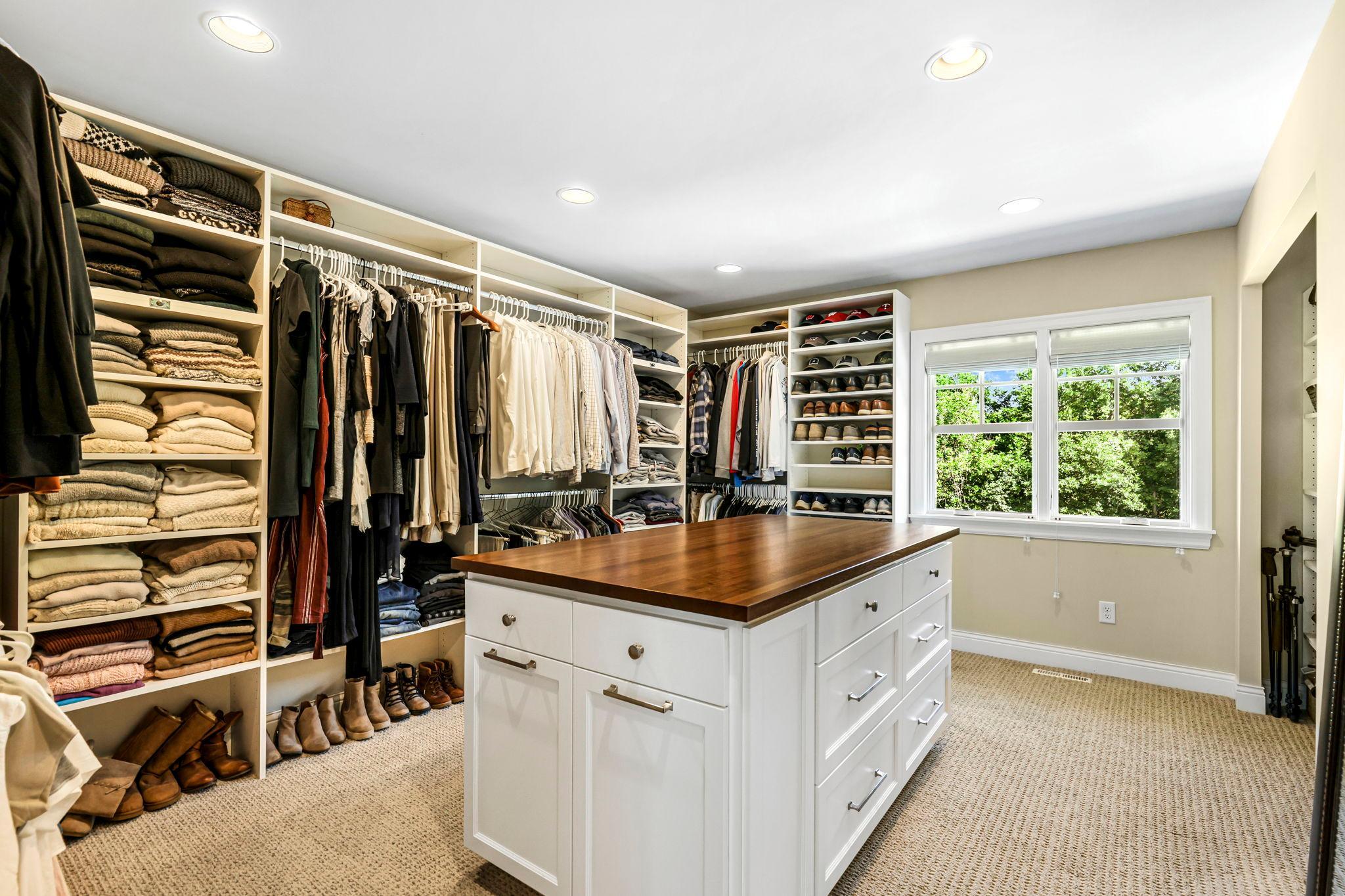Talk about a primary closet! Tons of built in shelving and built in "island."