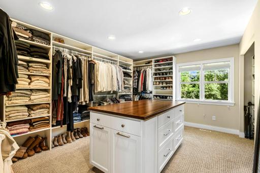 Talk about a primary closet! Tons of built in shelving and built in "island."