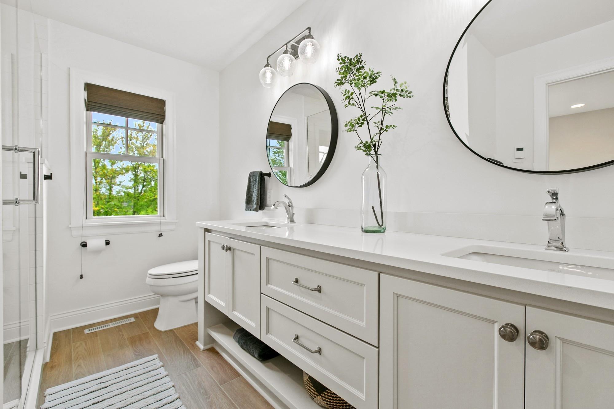 Each bedroom has its own private bathroom! This one is in the back of the home and is attached to bedroom two. It features heated tiled flooring, quartz countertops, a dual vanity and a large walk-in shower.