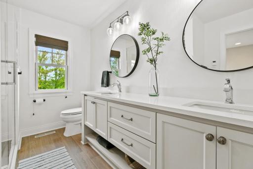 Each bedroom has its own private bathroom! This one is in the back of the home and is attached to bedroom two. It features heated tiled flooring, quartz countertops, a dual vanity and a large walk-in shower.