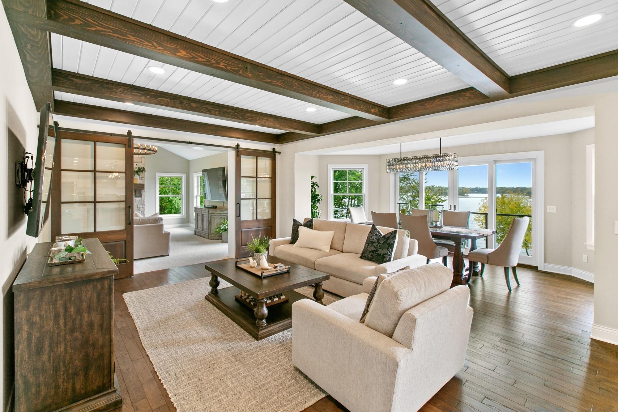 The inviting living room situated on the main level features handsome wood beams and hardwood flooring. Barn doors can close off the sunroom for privacy.