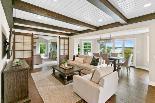 The inviting living room situated on the main level features handsome wood beams and hardwood flooring. Barn doors can close off the sunroom for privacy.