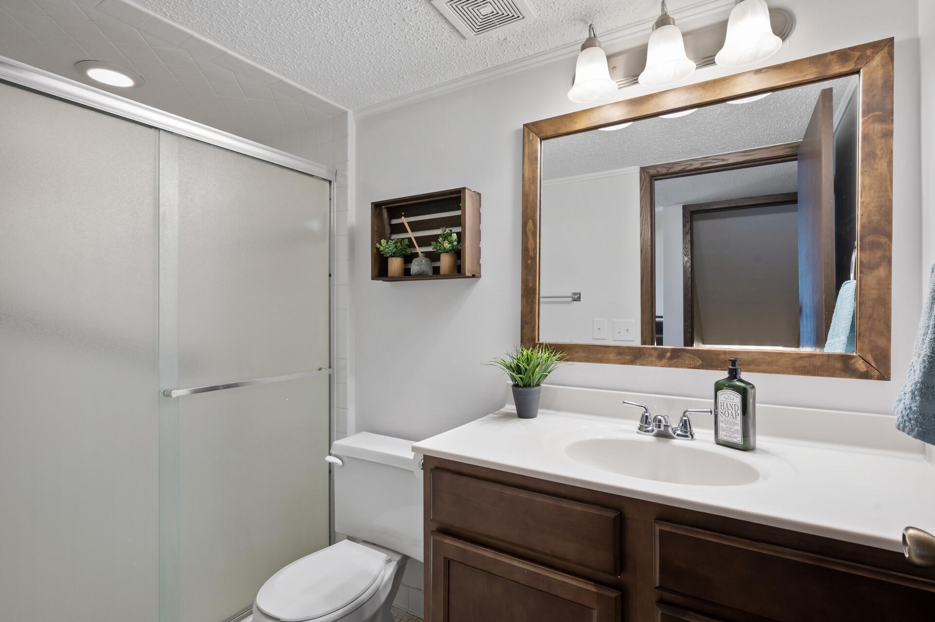 The three-quarter bathroom on the main level has been freshly painted and features an oversized vanity with ample storage space and a walk-in shower.