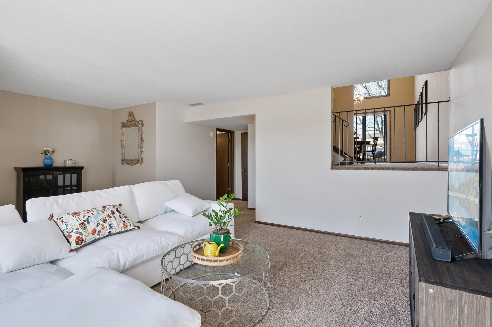 The living room is open to the dining room on the upper level. The open door at the far end of the room is the three-quarter bathroom.